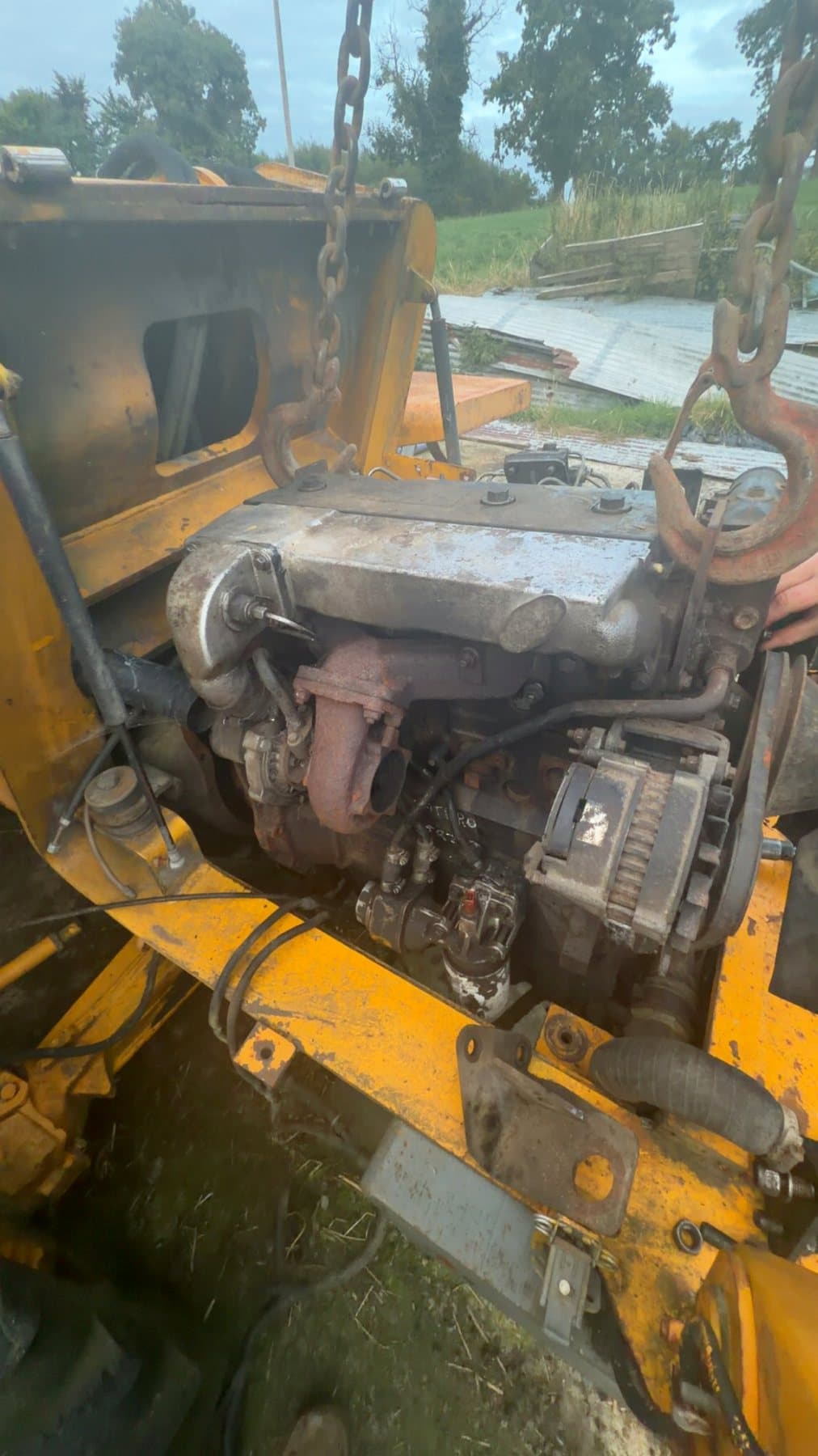Engine being removed from yellow plant machinery for repair