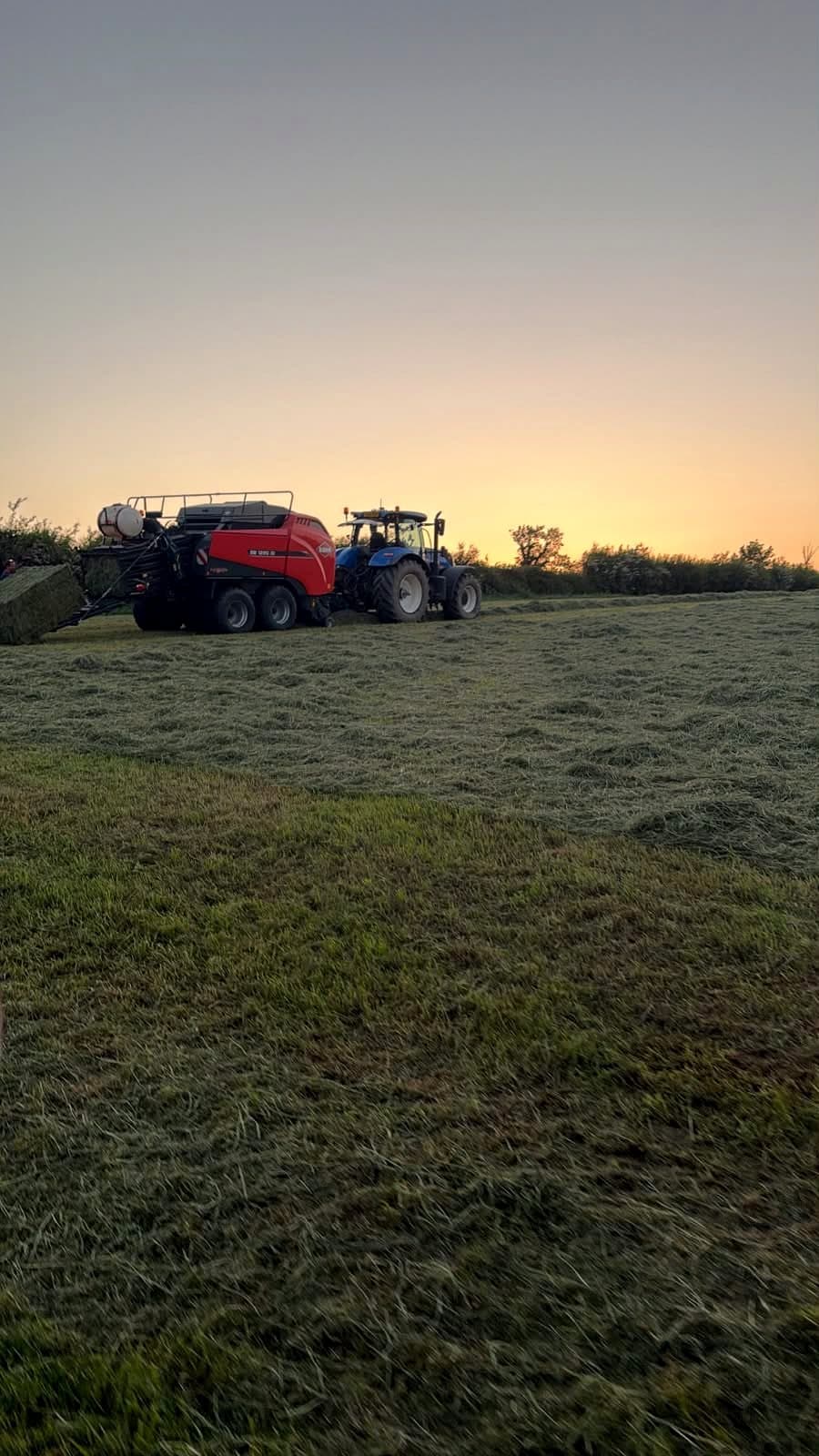 Agricultural harvesting machinery working at sunset